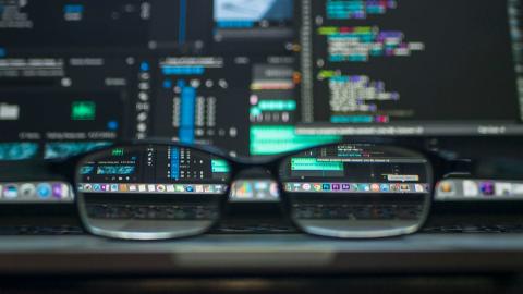 A pair of spectacles in front of computer screens