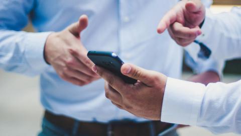 Businessmen gesticulating and discussing contents on a smartphone