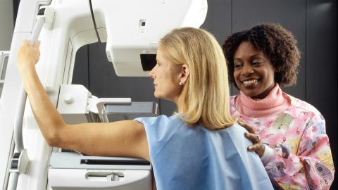 A woman undertakes a mammogram with a female HCP