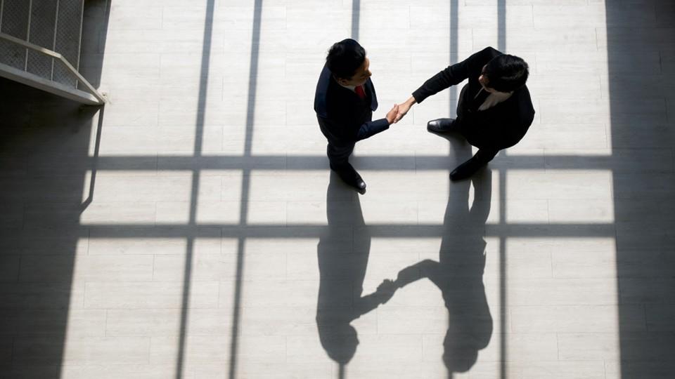 two men shake hands in a lobby