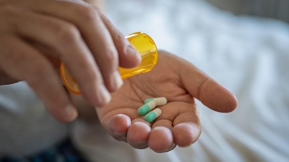 Pills from bottle without label into palm of a man's hand
