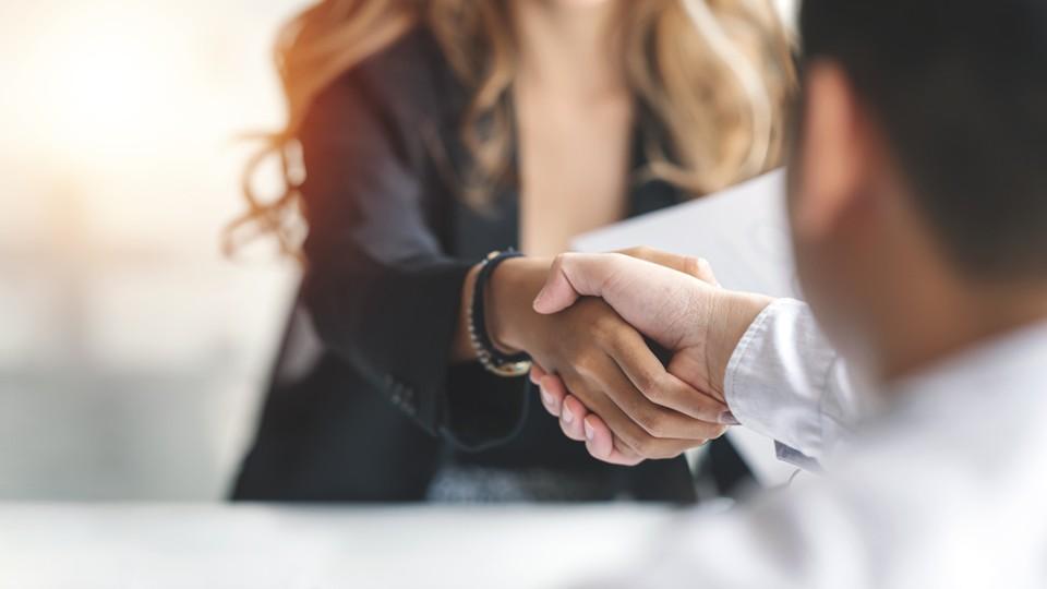 Woman shakes man's hand in hiring process