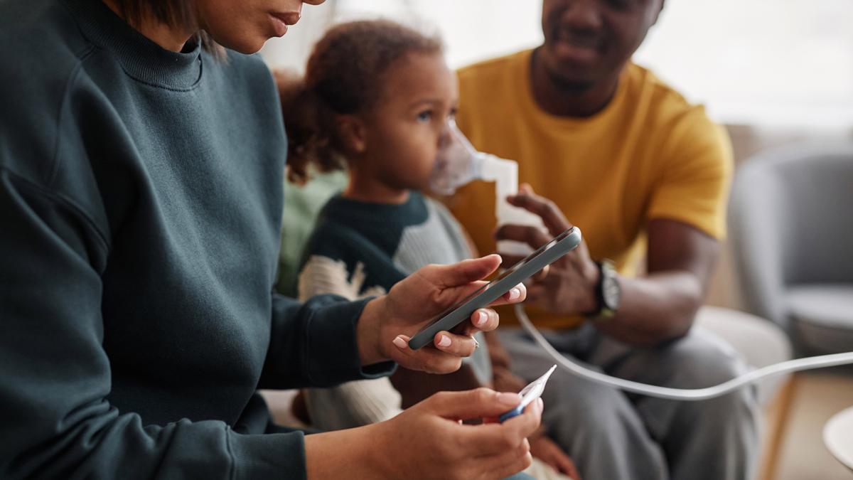 steaming nebulizer mask in hand instructing African American daughter