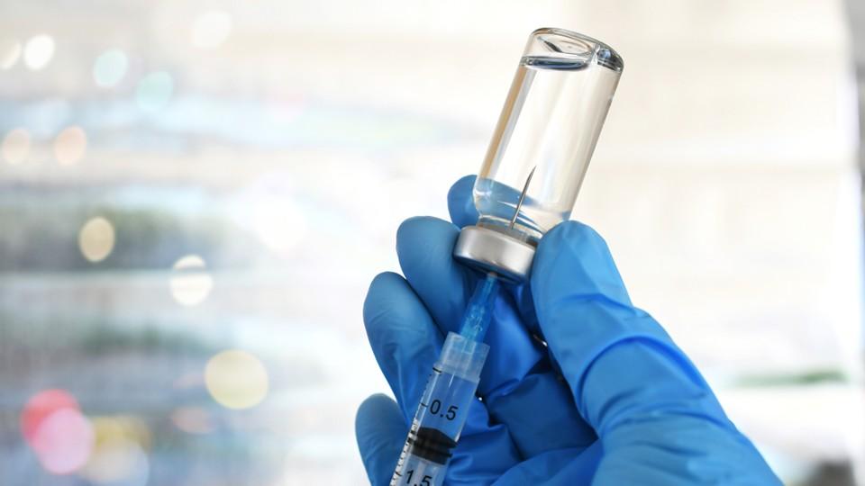 Surgically gloved hands prep a vaccine