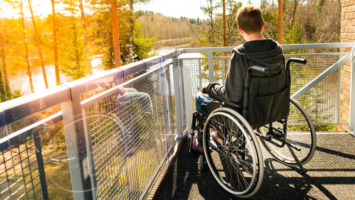 Boy in a wheelchair looking out to the forest