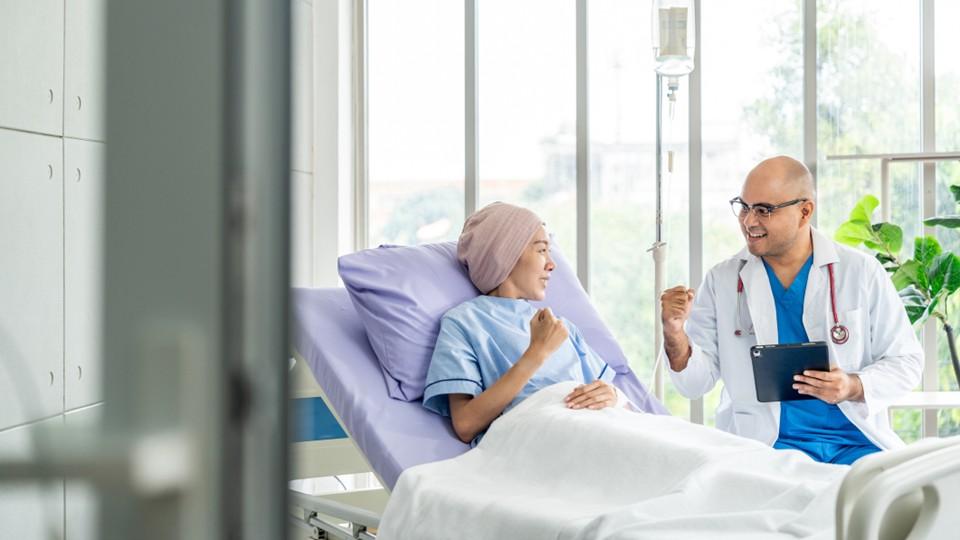 Cancer patient in hospital bed speaking with doctor