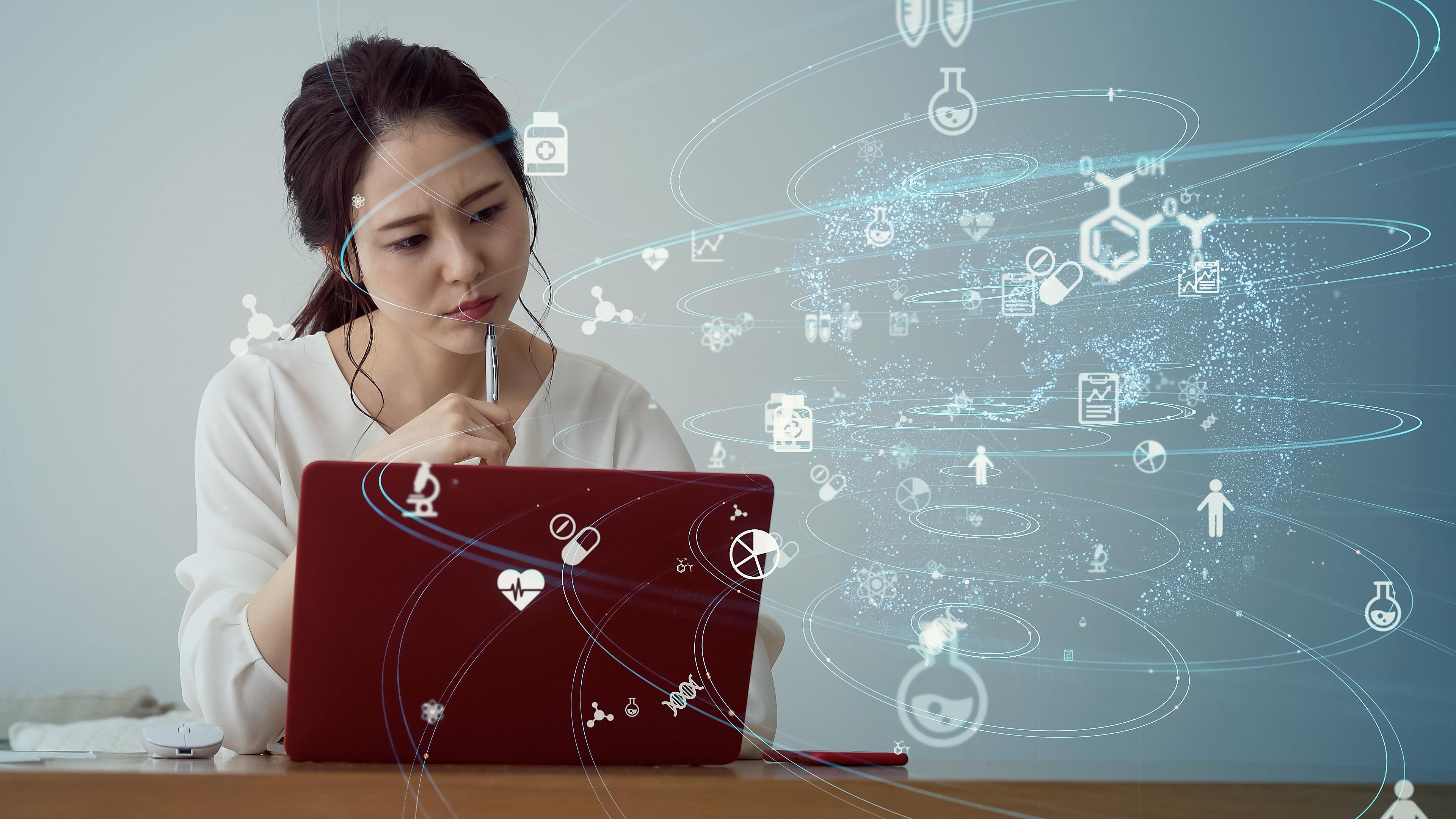Digitally collated information assessment by an Asian woman at her laptop