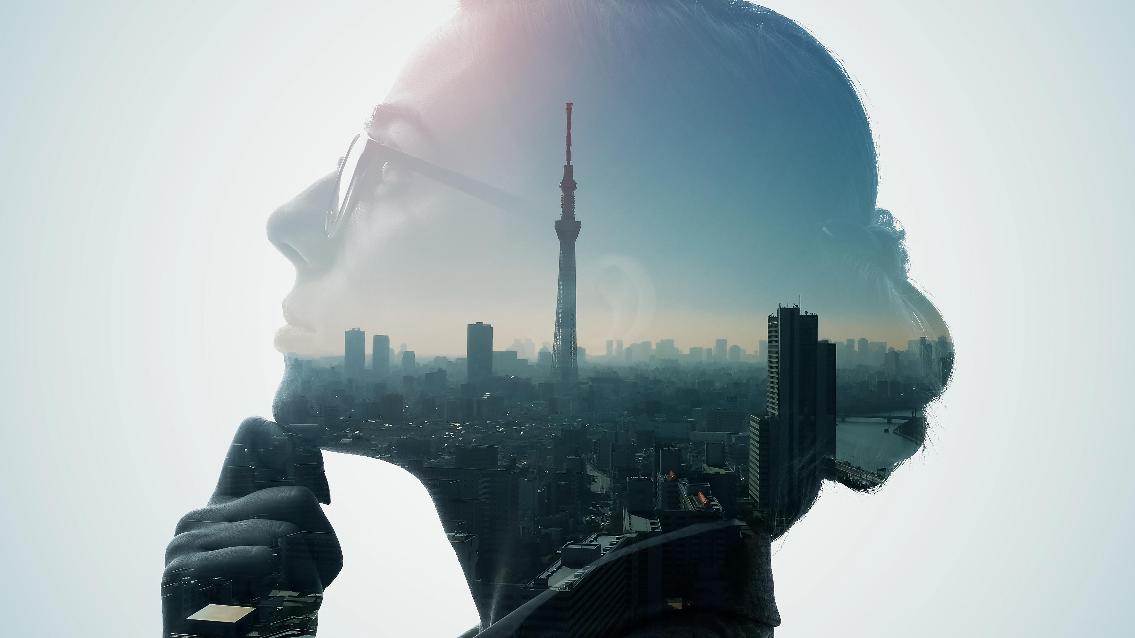 Silhouette of a female thinking side profile face overlaid on a cityscape