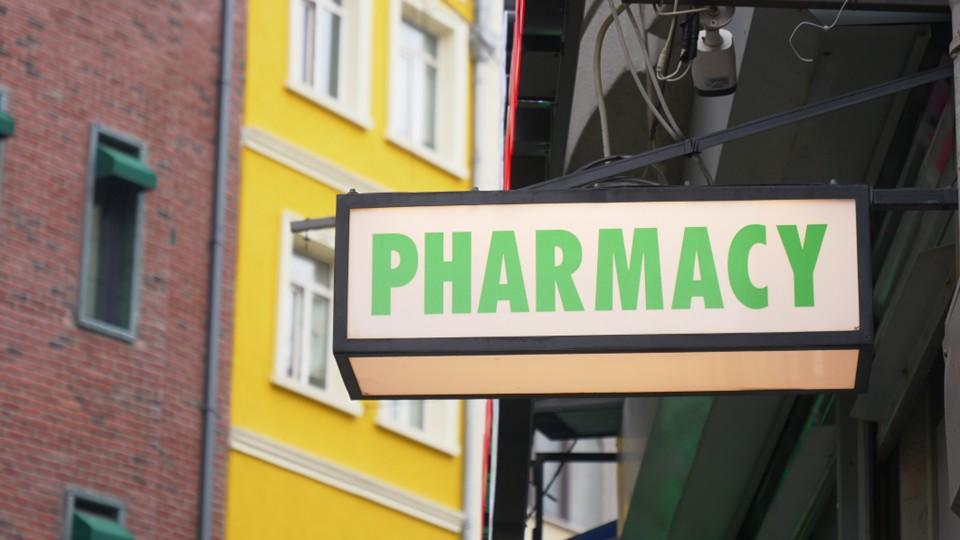 Pharmacy sign with yellow townhouse in background
