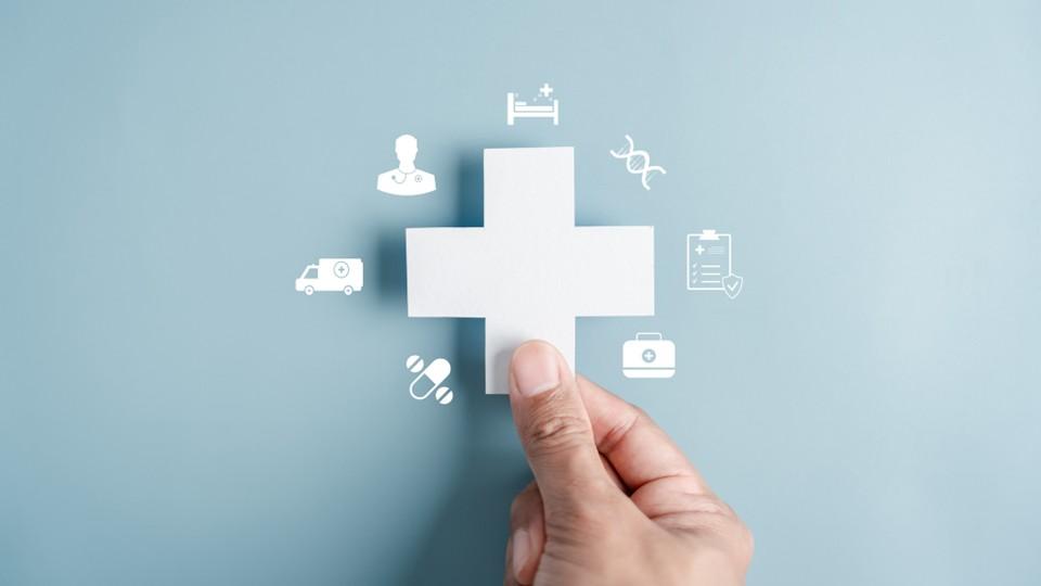 Hand holds white cross with digital symbols surrounding against light blue background