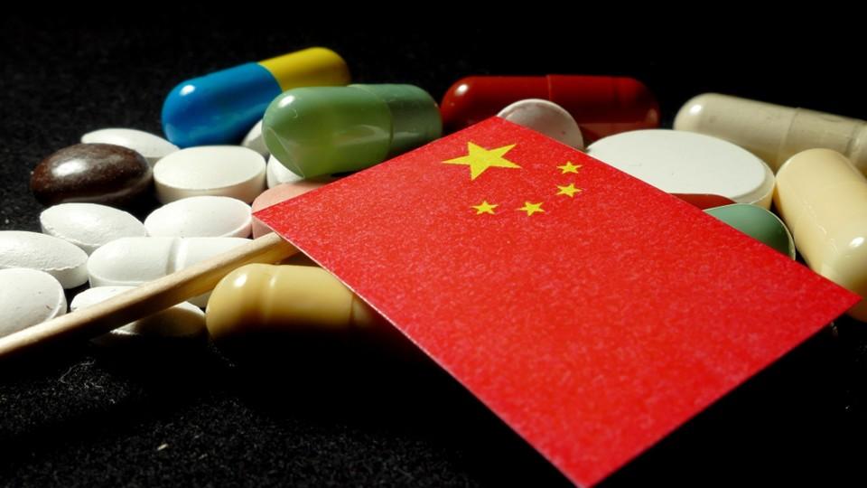 Chinese flag atop pills on black background