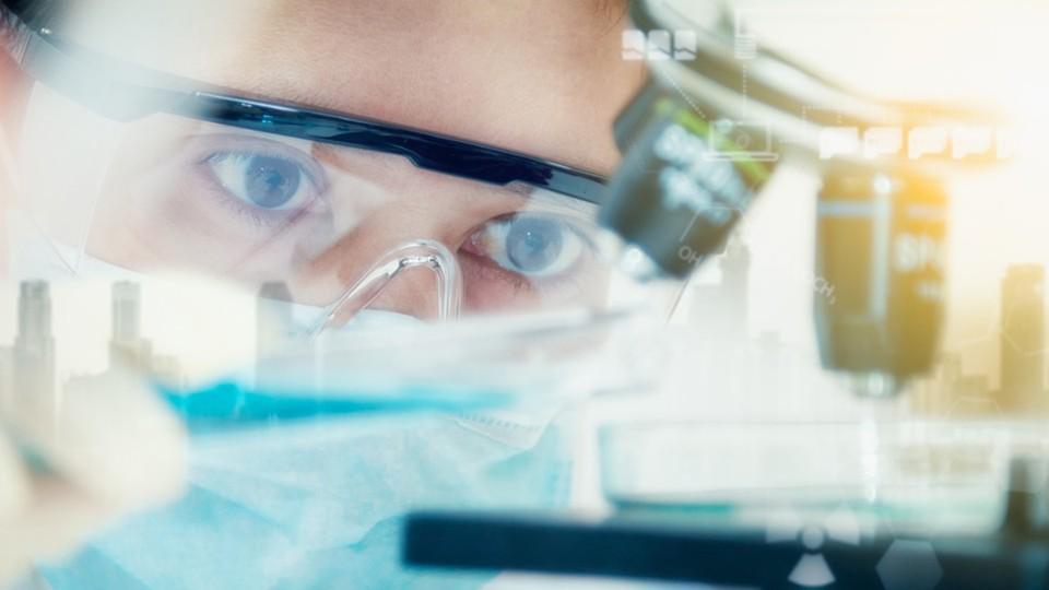 Female scientist uses a microscope
