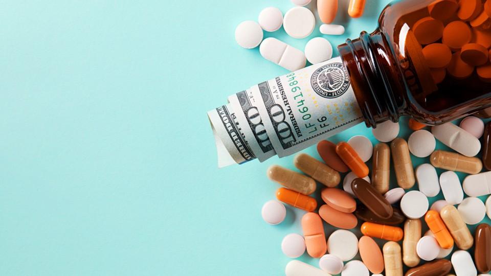 $100 notes in pill bottle on aquamarine background with spilled pills