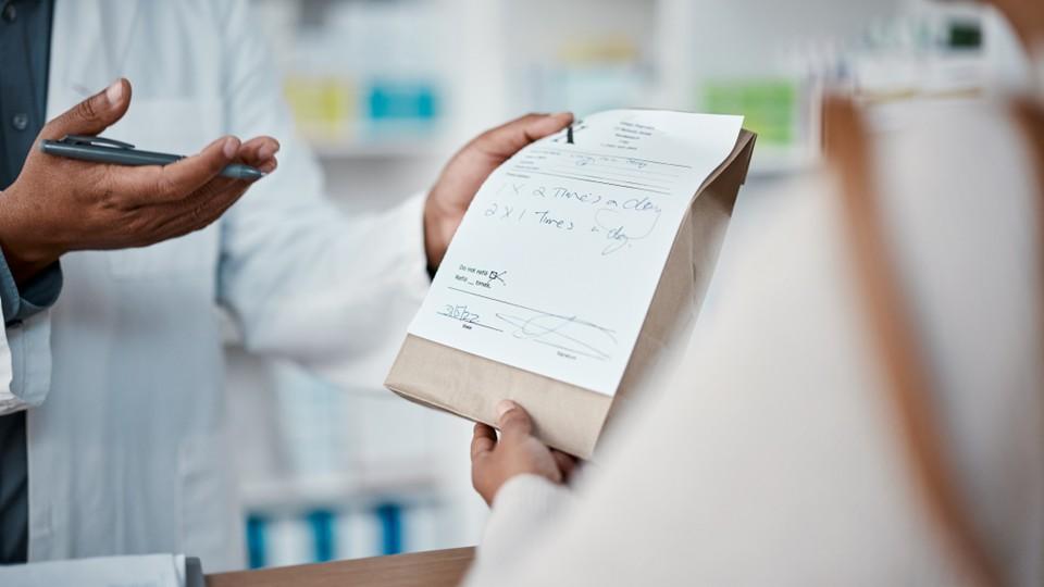 Pharmacist hands woman prescription medicine with an explanation