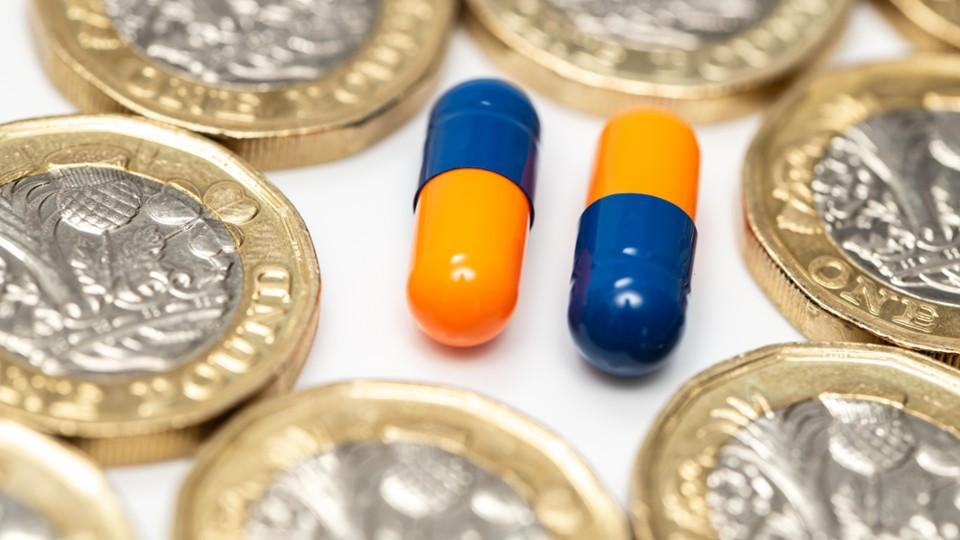 Two pills in the middle of multiple £1 coins