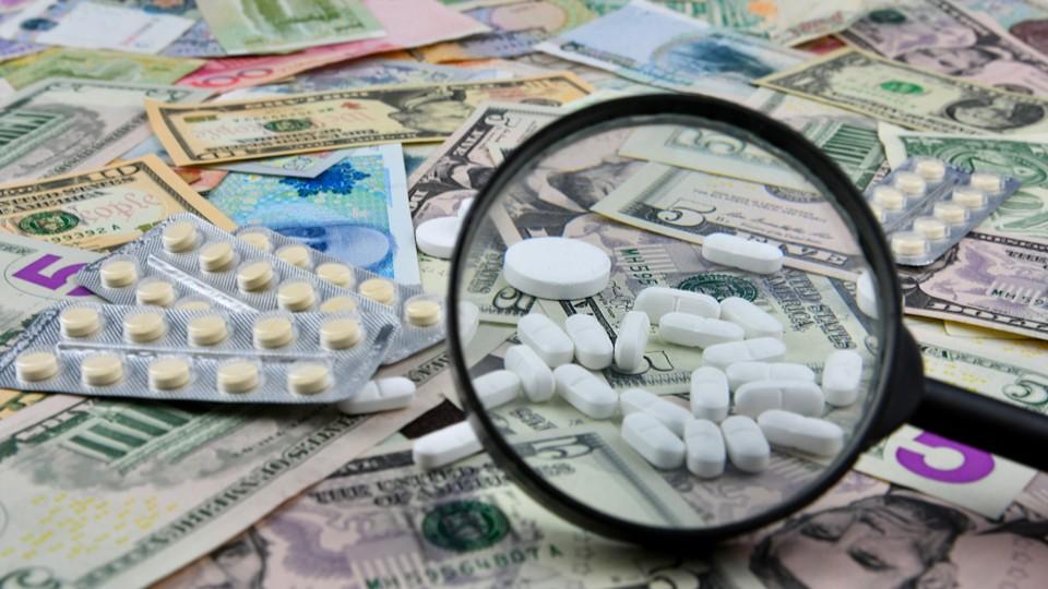 Magnifying glass over pills scattered over dollar and euro notes
