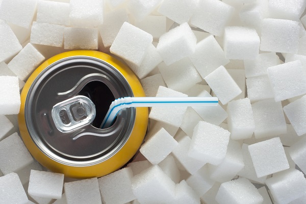 Unhealthy food concept - sugar in carbonated drink. Sugar cubes as background and canned drink
