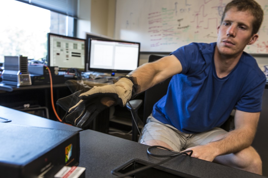 GRIDLab member David Caldwell tests the hardware used for stimulating and recording a patient’s brain surface, along with a cyber glove to track the hand's movement. Mark Stone/University of Washington