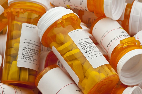 Bottles of prescription medicine in a pile. This collection of pill bottles is symbolic of the many medications senior adults and chronically ill people take.