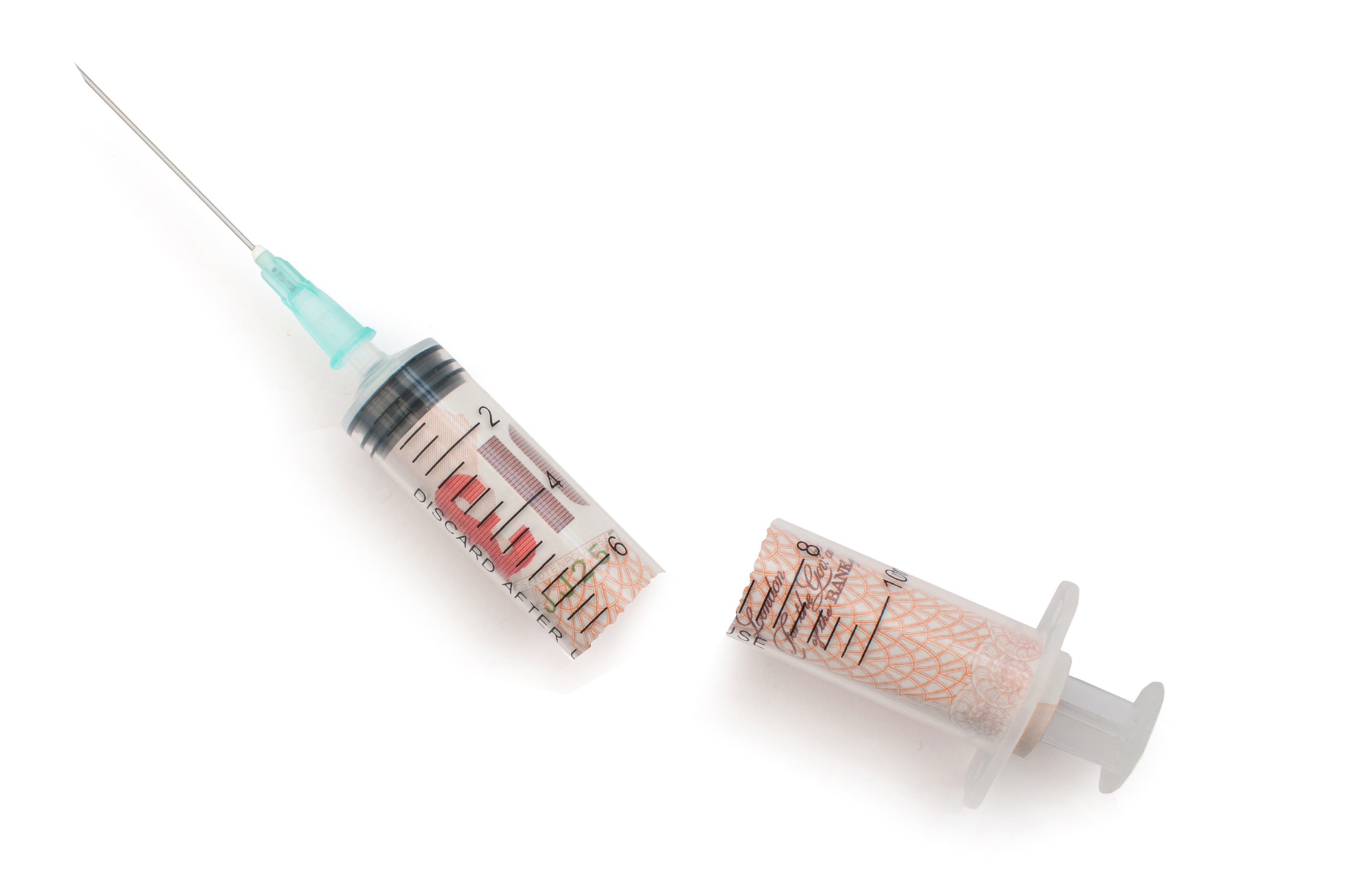 Broken injection syringe containing uk banknotes over a white background