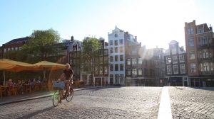 bicycle rider on cobblestone bridge in afternoon sunlight, Amsterdam