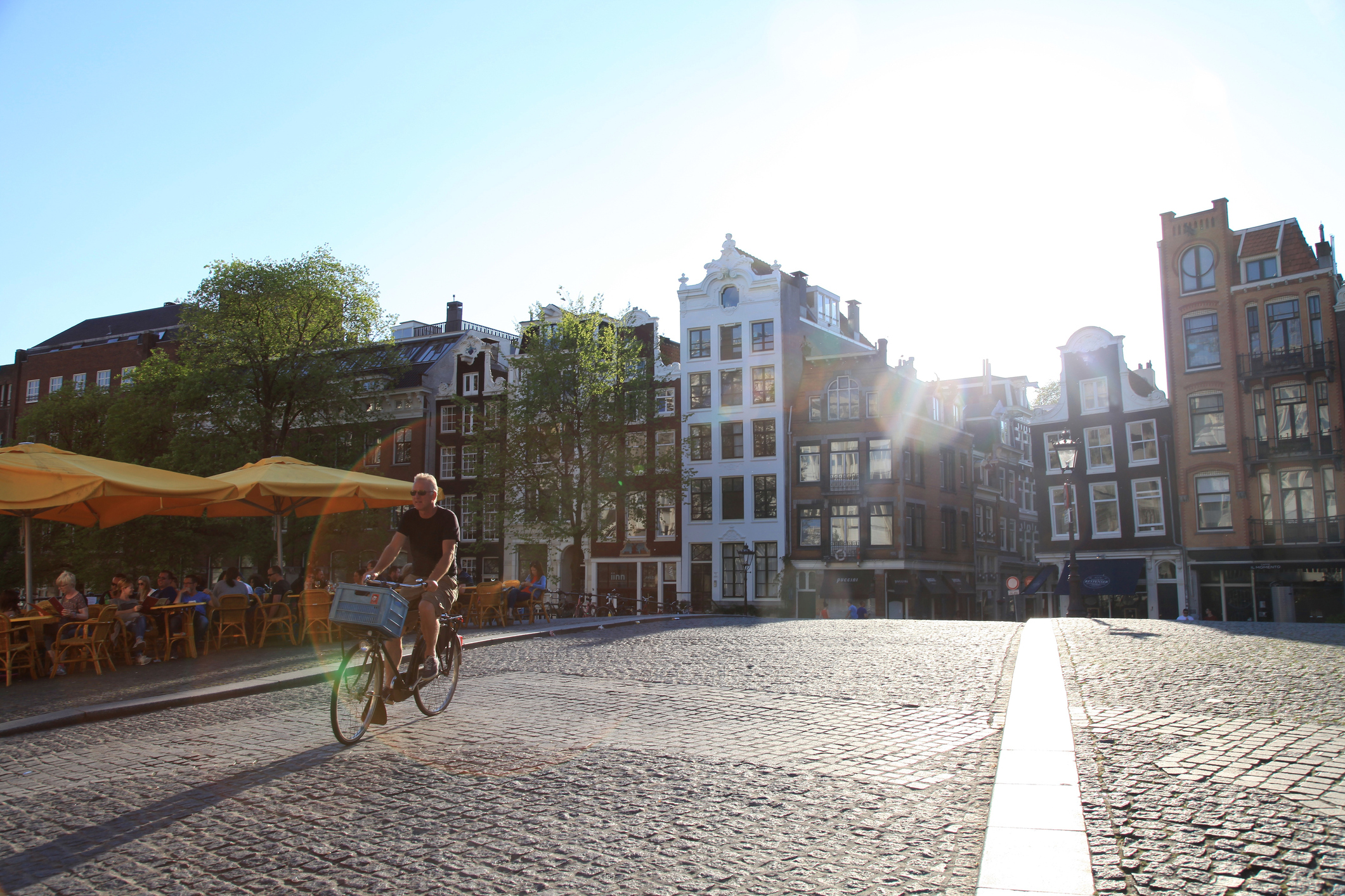 Amsterdam, Netherlands - May 8, 2016: Street scene with bicycle rider on cobblestone bridge in the afternoon sunlight, Amsterdam, Netherlands.