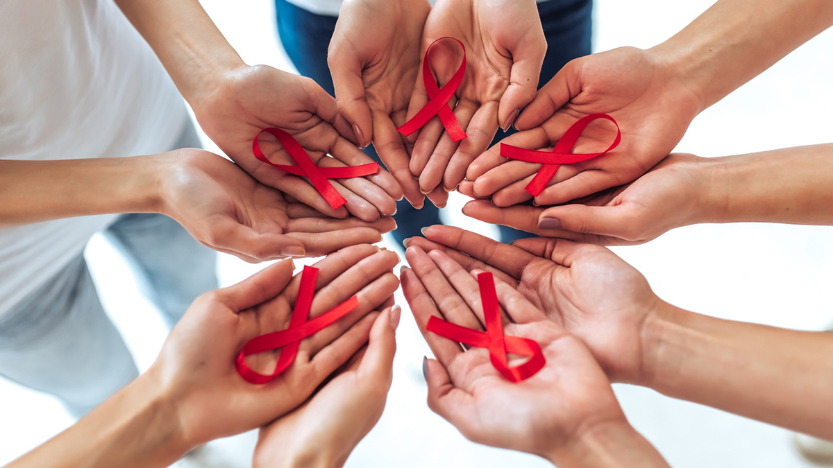 Group of young multiracial woman with red ribbons in hands are struggling against HIV/AIDS. AIDS awareness concept.
