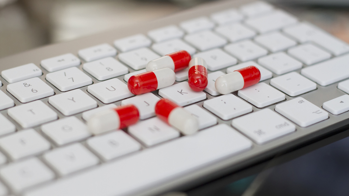 Some red and white pills over computer keyboard