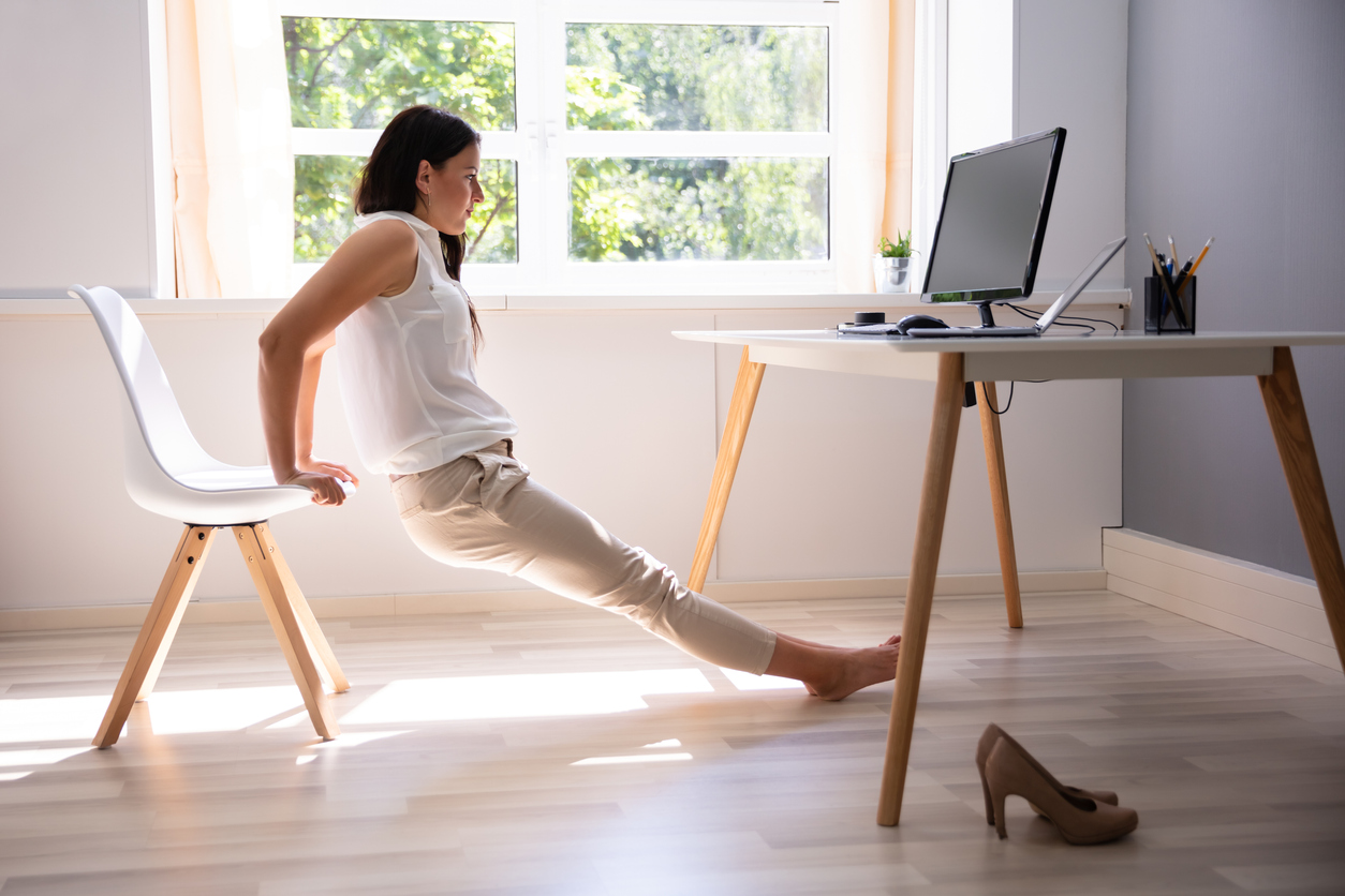 Side View Of A Young Woman Doing Stretching Exercise In Office