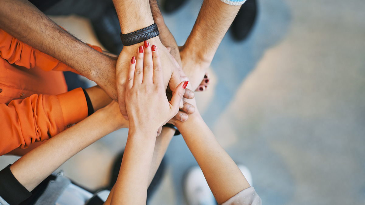 Multiethnic group of young people putting their hands on top of each other. Close up image of young students making a stack of hands.