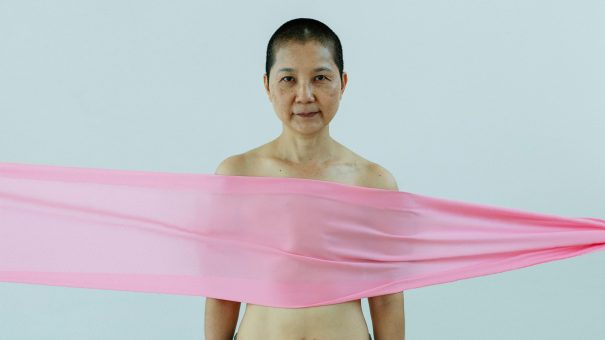 Breast cancer survivor with a pink ribbon spread across her chest